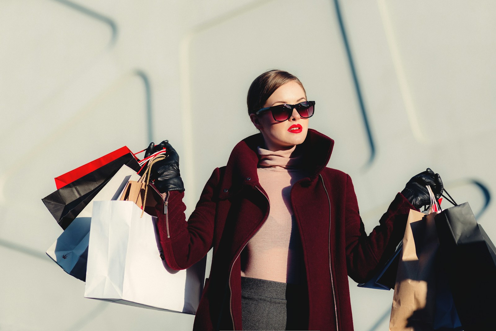 A shopper wearing a burgundy coat and carrying shopping bags